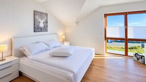 A bedroom with a bed, a nightstand, a lamp, a window with blinds, and a view of the outdoors. - Mountain View - Charming townhouse for 4 people with an infrared sauna (Winterberg)