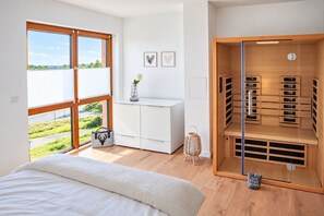 A bedroom with a large window, a bed, a white dresser, and a built-in closet with shelves. - Mountain View - Charming townhouse for 4 people with an infrared sauna (Winterberg)
