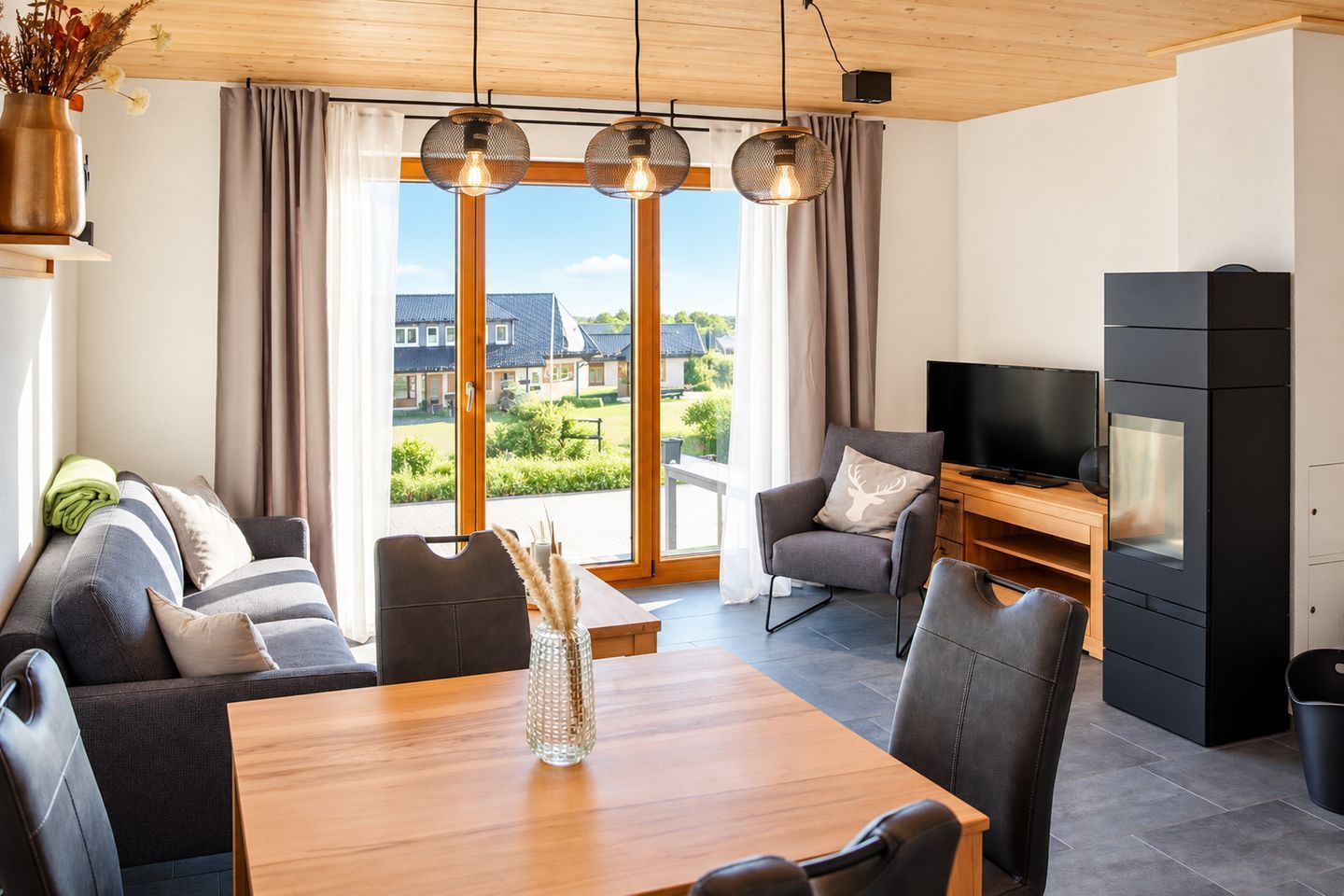 A modern living room with a sofa, dining table, chairs, a TV, and a fireplace.