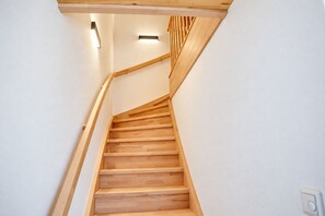 A wooden staircase with a handrail and a light fixture above it.
