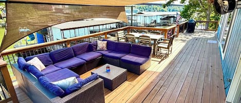 Um deck externo com sofá modular, uma mesinha e uma churrasqueira.