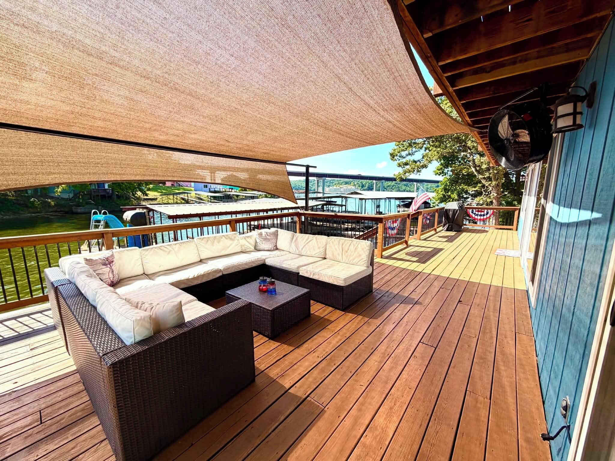 Een overdekt terras met een bank en een tafel, met uitzicht op water en een brug.