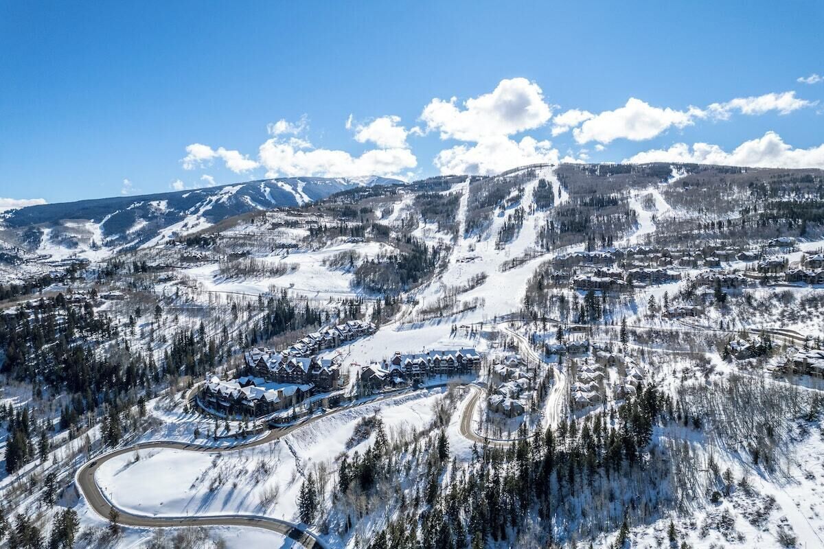 A snow-covered mountainous area with a resort complex featuring multiple buildings, roads, and ski slopes.