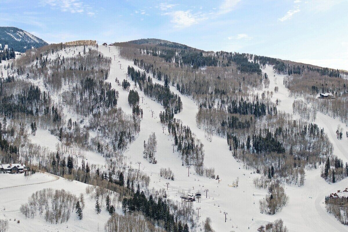 Une montagne enneigée, dotée de remontées mécaniques et d’un chalet.