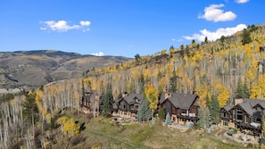 A mountain lodge with multiple cabins, surrounded by autumn foliage and a clear sky.
