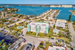 An aerial view of a coastal residential area with a prominent hotel featuring a modern design, located near a marina with boats.