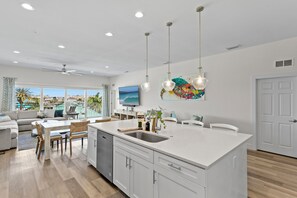 A modern kitchen with a large island, white cabinetry, and pendant lighting. - Luxury Beach Penthouse at Madeira Del Mar (Madeira Beach)