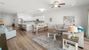 A modern living room with a sofa, coffee table, and a dining area with chairs and a table.