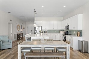 A spacious kitchen with white cabinets, a central island with seating, and a stainless steel refrigerator. - Luxury Beach Penthouse at Madeira Del Mar (Madeira Beach)