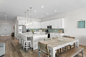 A modern kitchen with white cabinetry, a central island, and pendant lighting. - Luxury Beach Penthouse at Madeira Del Mar (Madeira Beach)
