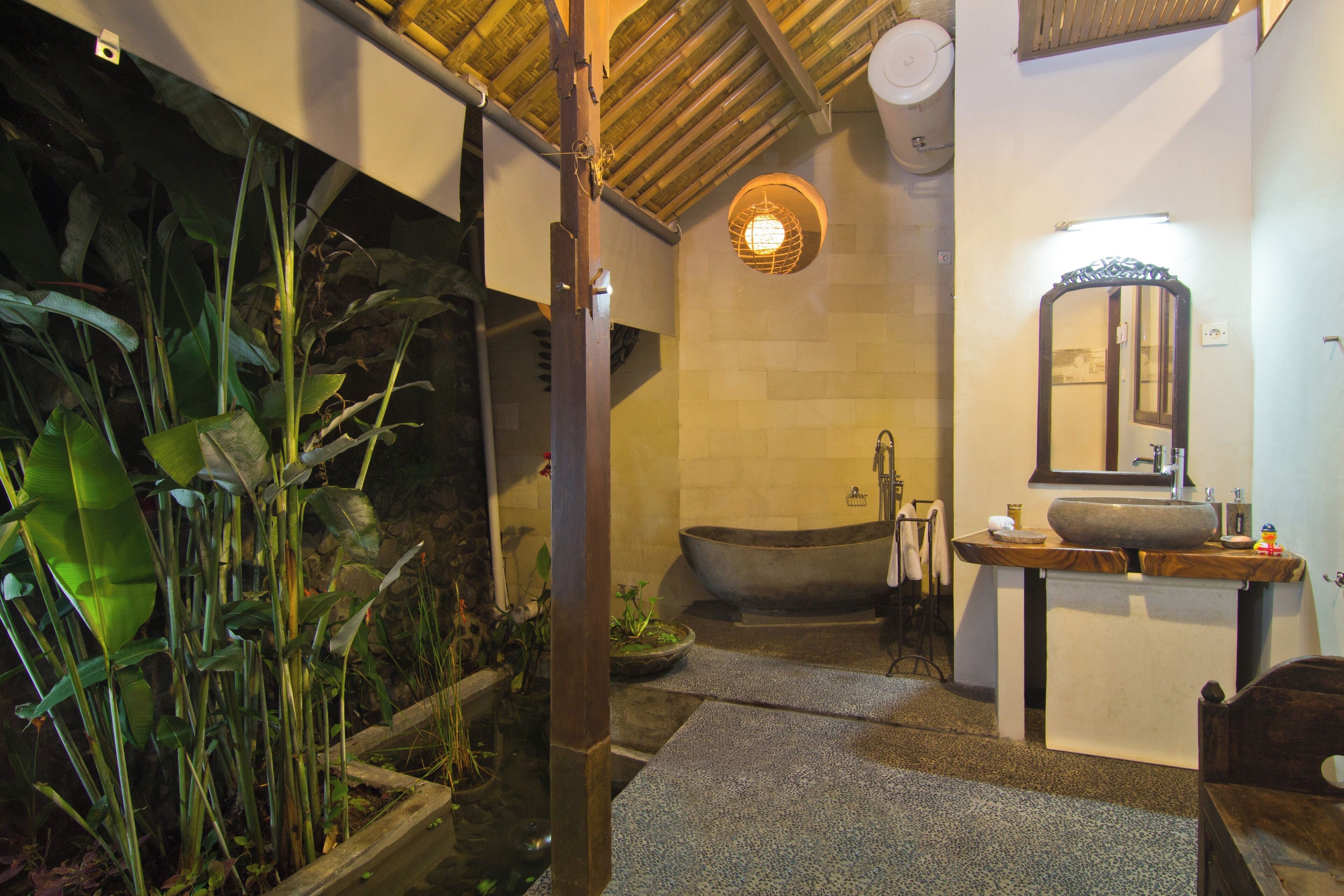 Une salle de bain avec une baignoire, un lavabo, un miroir et un petit espace dédié aux plantes.