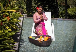 Eine Person sitzt am Pool mit einem Tablett voller Speisen und Getränke.