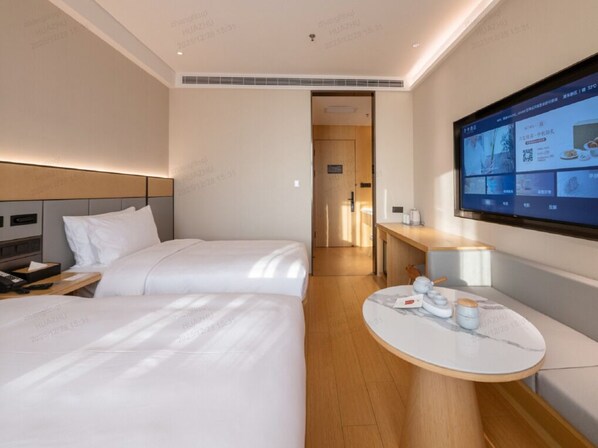 A hotel room with two beds, a small table with a TV, and a wooden desk. - Ji Hotel Shanghai Pudong Airport Free Trade Zone (Shanghai)