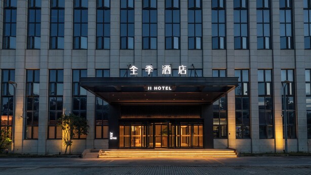 A hotel entrance with a modern facade, large windows, and a sign indicating it is the Ji Hotel. - Ji Hotel Shanghai Pudong Airport Free Trade Zone (Shanghai)
