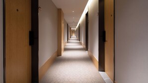 A long, narrow hotel corridor with wooden doors on both sides, a tiled floor, and recessed lighting. - Ji Hotel Shanghai Pudong Airport Free Trade Zone (Shanghai)