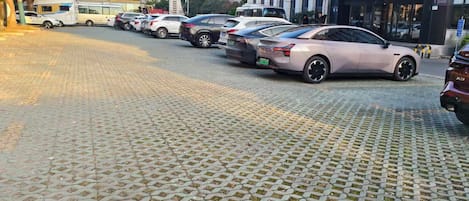 A hotel entrance with a covered walkway and parked cars.