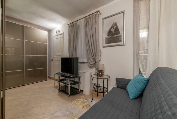 Una sala de estar moderna con un sofá, un televisor, una mesita y un aparador de vidrio.