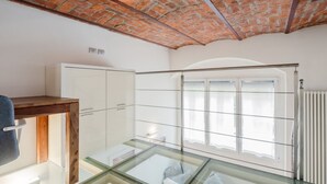 Ein Zimmer mit Glastisch, weißen Schränken, einem Holztisch und einer Ziegeldecke.