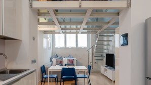 Eine kleine Küche mit Essbereich, einem Fernseher und einer Treppe zu einer oberen Ebene.