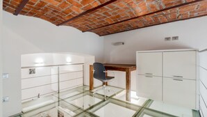 Ein Zimmer mit Glastisch, Holzbüro, Stuhl und weißen Schränken.