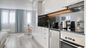 Een moderne keuken met witte kastjes, een zwart aanrecht en roestvrijstalen apparatuur. Er is een gezellig eethoekje met een tafel en stoelen.