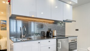 A modern kitchen with a sleek design, featuring a stainless steel refrigerator, a built-in oven, and a coffee maker on the countertop.