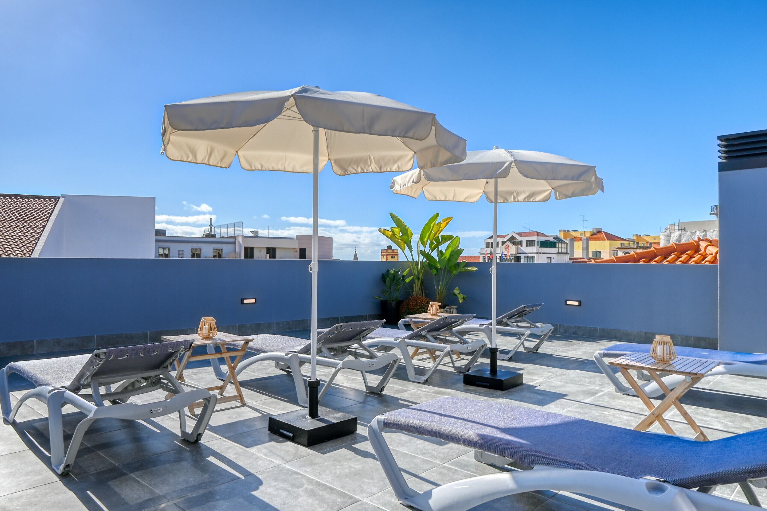 Un espace de détente aménagé sur le toit, avec des chaises longues, des parasols et des plantes en pot.