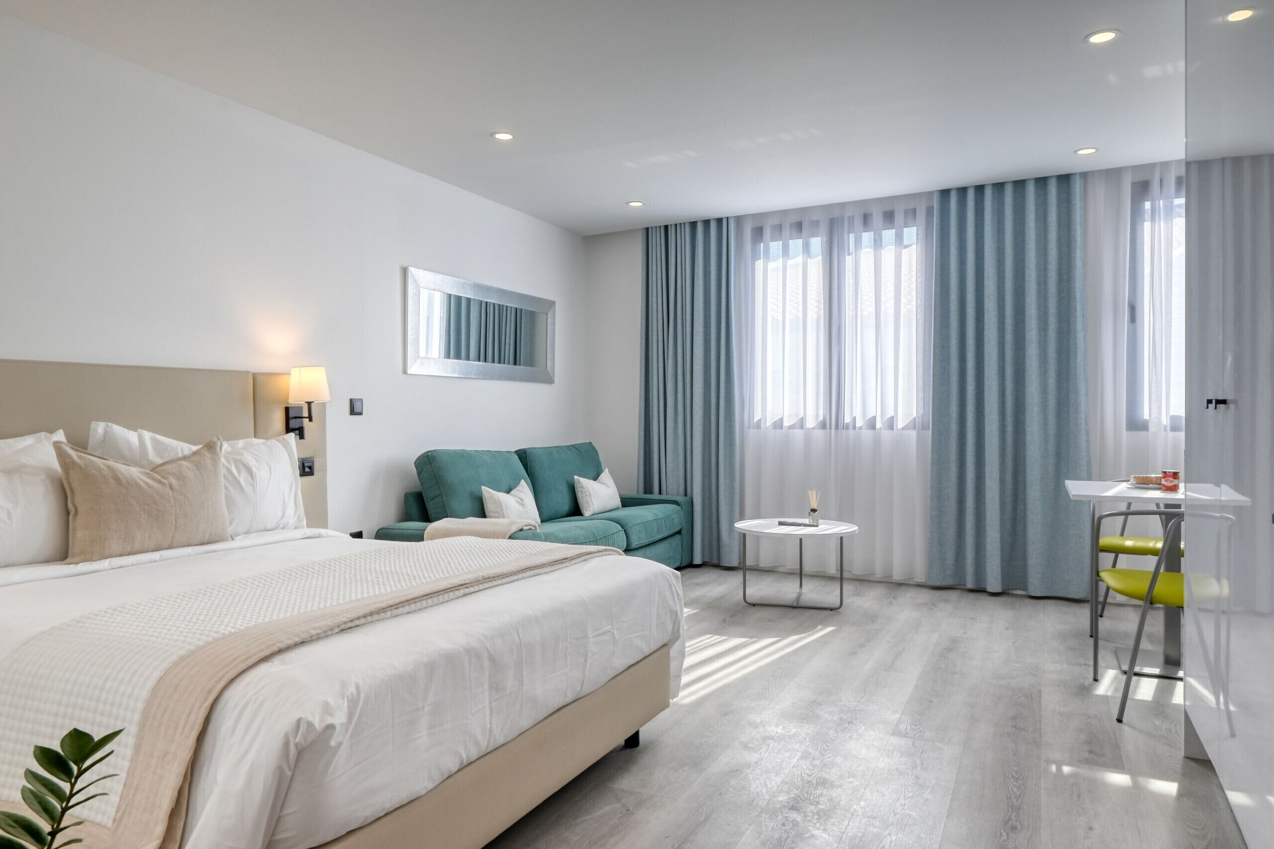 Een moderne hotelkamer met een groot bed, een bank, een klein tafeltje en een stoel.