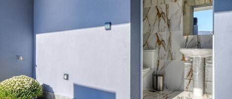 A modern bathroom with marble tiles, a sink, and a WC sign.