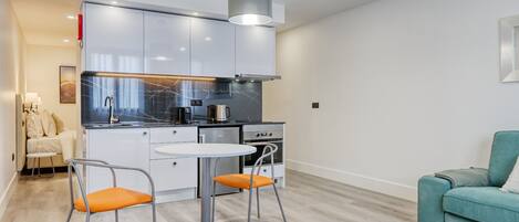 Cocina moderna con armarios blancos, encimera negra y una isla central con asientos.