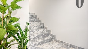 En elegant trappe i marmor med et moderne design, en potteplante og et minimalistisk skilte på væggen.