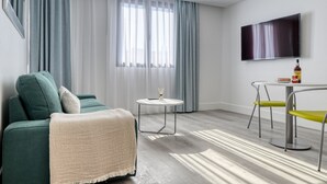 A modern living room with a green sofa, a small round table, and a TV mounted on the wall. - BSE15 Apartments 4L, a Home in Madeira (Funchal)