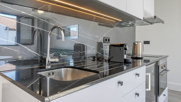 A modern kitchen with a black countertop, stainless steel sink, and a coffee maker. - BSE15 Apartments 4L, a Home in Madeira (Funchal)