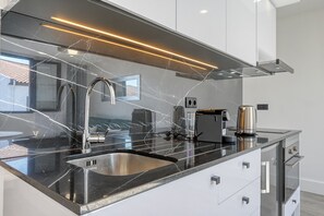 Eine moderne Küche mit schwarzem Arbeitsplatz, Spüle aus Edelstahl und einer Kaffeemaschine.
