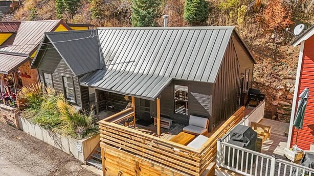 A cabin with a sloped roof, a deck with seating, and a small outdoor area with a grill. - Daly Cottage | Walk to Main | Monthly Rentals Ava. (Park City)