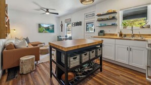 A modern kitchen with white cabinets, a wooden island, and a ceiling fan. - Daly Cottage | Walk to Main | Monthly Rentals Ava. (Park City)