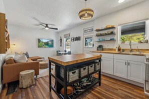 A modern kitchen with white cabinets, a wooden island, and a ceiling fan.