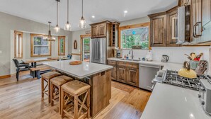 Une cuisine spacieuse avec des meubles en bois, un grand îlot central et une cuisinière à gaz.