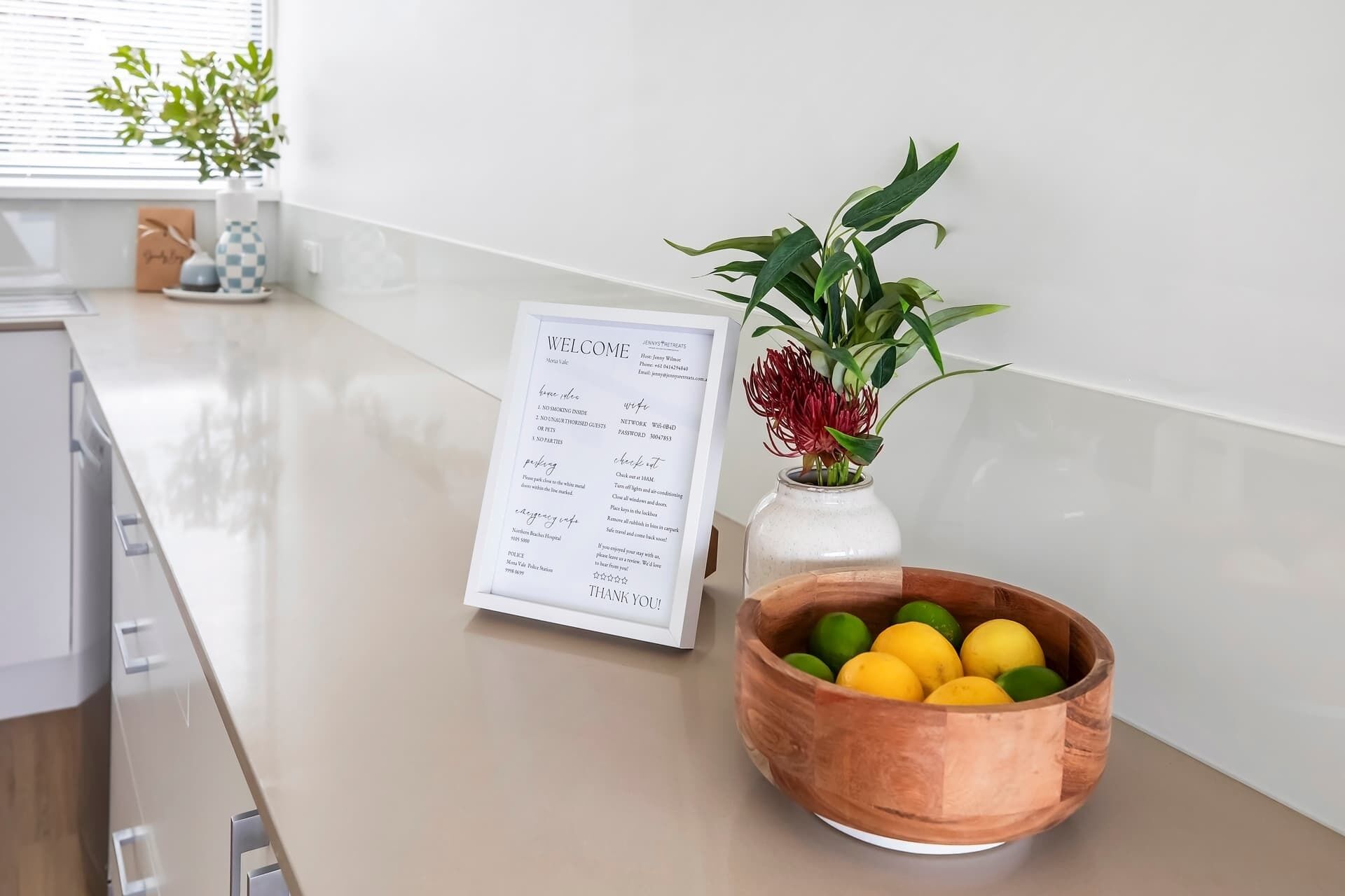 A kitchen counter with a menu, a vase with a plant, and a bowl of fruit.