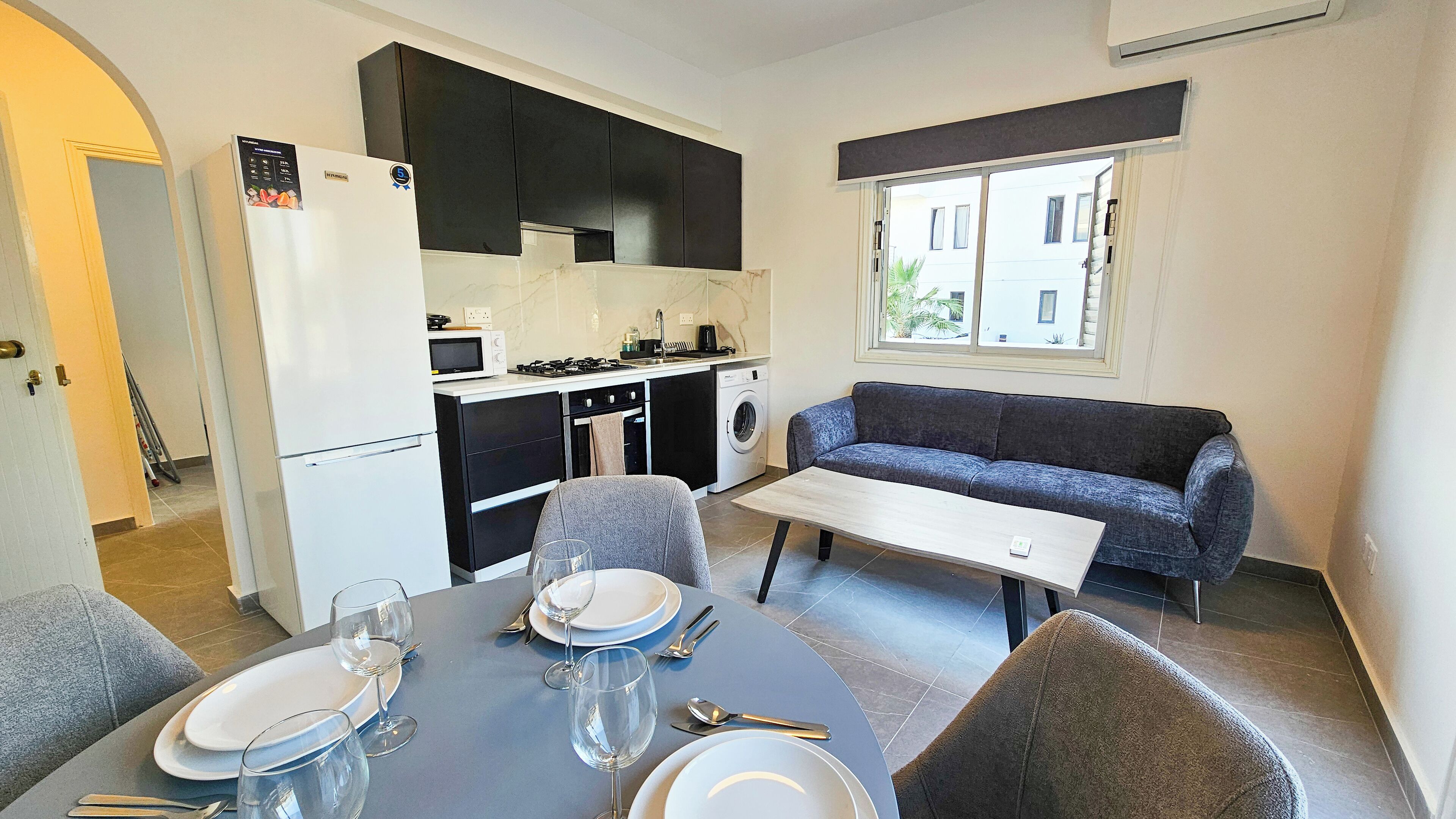Un espacio habitable compacto con kitchenette, comedor y sofá.