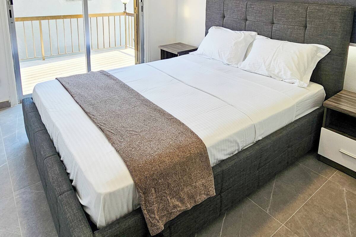 Une chambre à coucher comprenant un lit, une table de chevet et un appareil de climatisation.