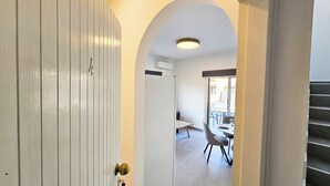 Un couloir avec une porte blanche, une porte en arc de cercle et un escalier.