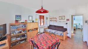 Een ruimtelijk ingerichte leefruimte met eethoek, kitchenette en een slaapbank.