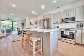 A modern kitchen with a central island, stainless steel appliances, and a dining area with a view.