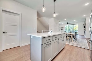 A modern kitchen with a central island, pendant lighting, and a dining area with a view.