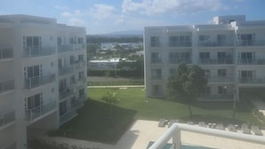 Blick auf ein modernes Apartmenthaus mit mehreren Balkonen, einem Schwimmbad und blauem Himmel.