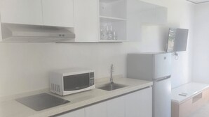 Eine moderne Küche mit weißen Schränken, einer Mikrowelle, einem Spülbecken und einem Kühlschrank.