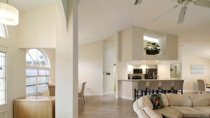A spacious living area with a large sofa, a dining table, and a kitchen in the background. - Stunning 3/2 pool home in the heart of Punta Gorda - Pelican Poolside (Punta Gorda)