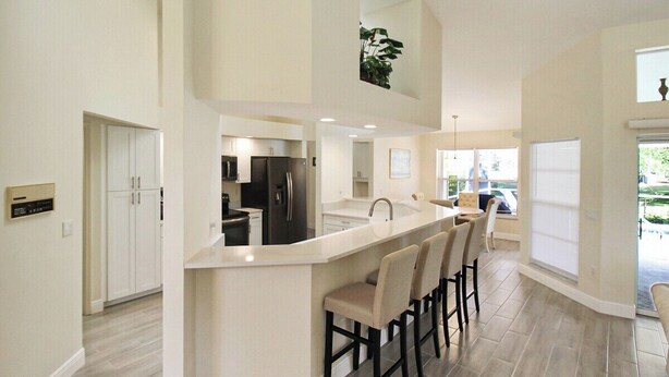 A modern kitchen with a central island, bar stools, and a view of the outdoors. - Stunning 3/2 pool home in the heart of Punta Gorda - Pelican Poolside (Punta Gorda)