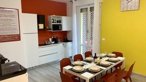 A modern kitchen with white cabinets, a microwave, and a sink. There is a dining table set with plates and glasses.